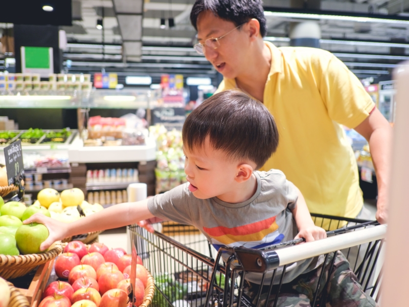 Asian father and son grocery shopping in fruit section